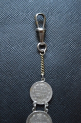 A 1915 COMMEMORATIVE CROSS & BONES WATCH FOB.